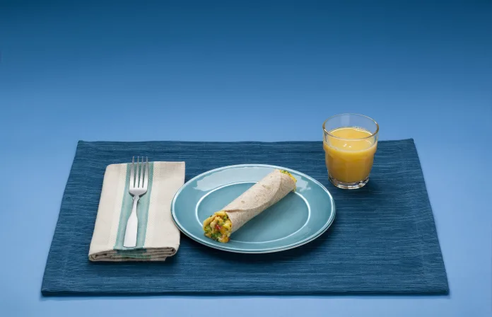 Wrap de café da manhã com ovos, queijo e legumes em prato azul