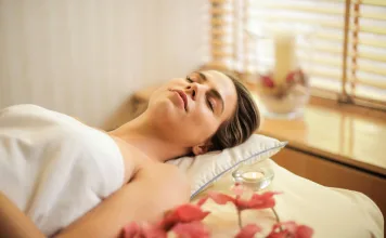 Como dormir melhor naturalmente: 12 estratégias práticas para vencer a insônia e acordar com mais energia Foto real de uma pessoa descansando em uma cama tranquila ao amanhecer