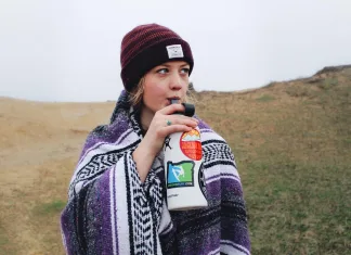 Hidratação ao longo do dia: 7 passos para beber água melhor Pessoa se hidratando ao longo do dia em ambiente externo